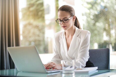 Eine Frau schaut konzentriert auf den Bildschirm eines vor ihr stehenden Laptops.